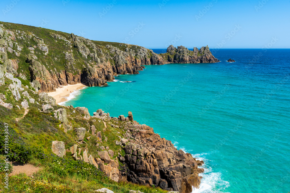 Fototapeta premium Turquoise waters and rugged cliffs along a picturesque coastal beach. Cornwall, UK. 
