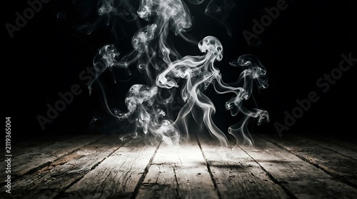 Dramatic wisps of white smoke forming a ghostly skull shape above a weathered wooden floor with moody lighting