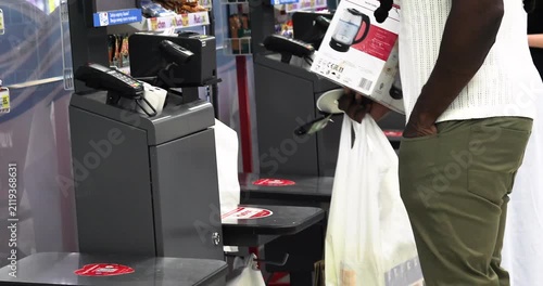 African man buys a kettle and pays at a self-checkout counter in a supermarket
