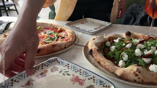 Male hands serving slice of artichoke pizza with spatula and fork onto plate at restaurant table, gourmet Italian cuisine, shared dining and authentic food experience