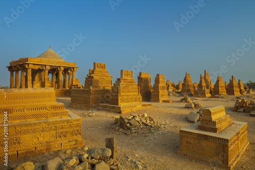 View of the historic Chaukhandi Tombs featuring intricate sandstone carvings and elaborate funerary architecture under a clear blue sky in the desert landscape, Karachi, Sindh, Pakistan.