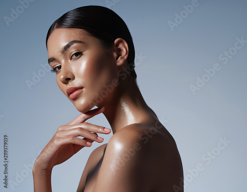 Elegant woman with radiant complexion posing with hand on chin in studio