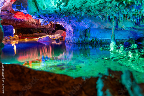 Foto Wide angle view of an illuminated underground cave with stalactites and colorful