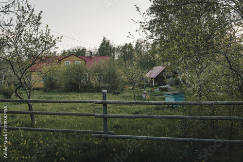 Laane County, Estonia - 19 May 2024: View of Vormsi island landscape featuring a traditional wooden house with a red roof, a wooden fence, and lush green grass in a quiet rural setting.