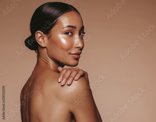 Elegant woman with glowing skin and sleek bun in studio beauty portrait
