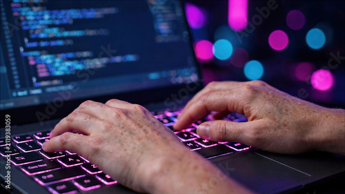 Close-up of a programmer's hands typing on a backlit laptop keyboard with source code on screen and colorful bokeh background