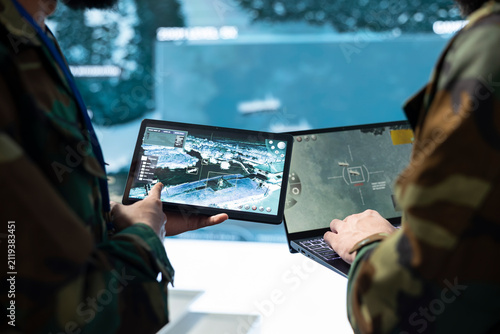 Foto Army personnel compare target information on tablets in the command center; team members review tactical surveillance imagery across device screens during threat monitoring and defense planning