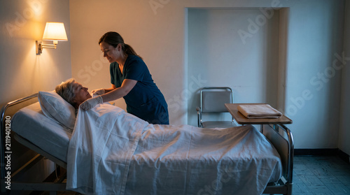 Night nurse refreshes bedding for a warm recovering patient