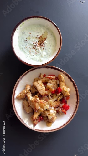 Top-down view of sizzling chicken fajitas with creamy tzatziki, fresh ingredients, rustic wooden table, vibrant Mediterranean dining