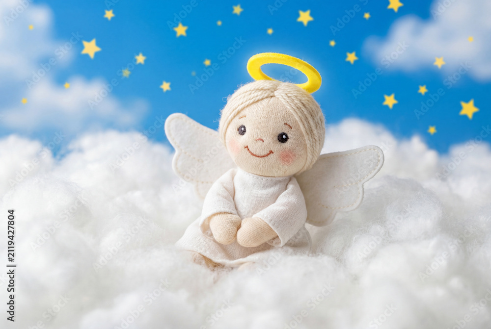Obraz premium Cute fabric angel doll with a yellow halo sits on fluffy white clouds beneath a starry blue sky