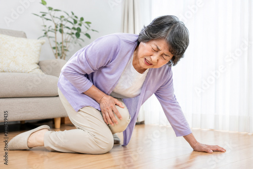 自宅で膝を痛めて倒れるシニア女性