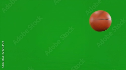 Overlay video transition, Orange basketball rolling across a bright green screen background for sports video production and chroma keying.