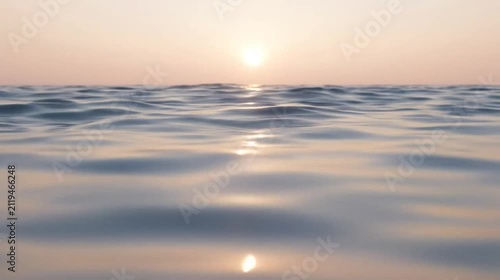 Gentle ocean waves reflecting sunset light horizon