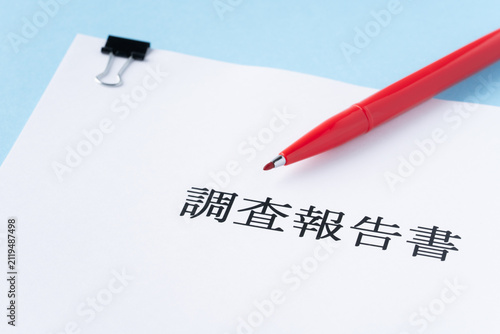 水色背景に調査報告書と赤いペン