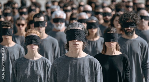 Diverse group of people wearing black blindfolds standing together outdoors