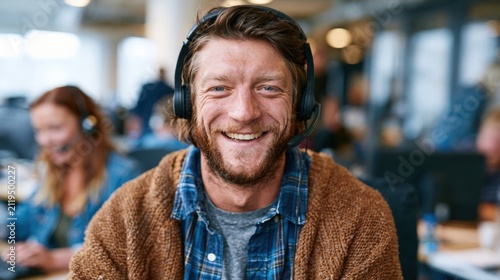 Smiling male customer service agent with headphones in a call center