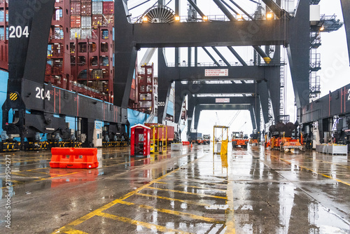 Modern container terminal with towering quay cranes working alongside a cargo vessel during loading operations at the Port of Houston, Texas, USA.