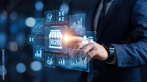Businessman touching digital screen with B2B ecommerce icons and financial charts