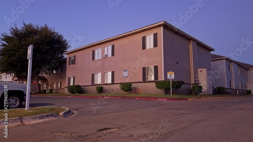 Evening exterior of a multifamily housing complex with a quiet street and fading sunset light.