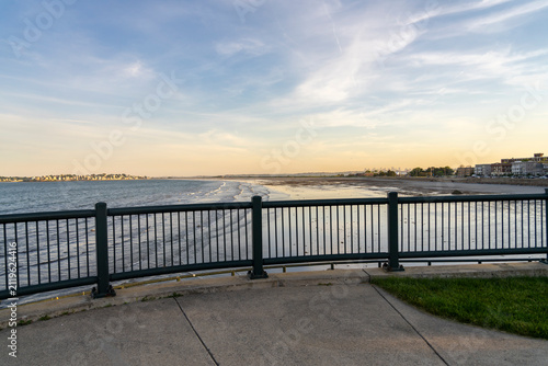 Oceanfront view with a railing and distant cityscape.