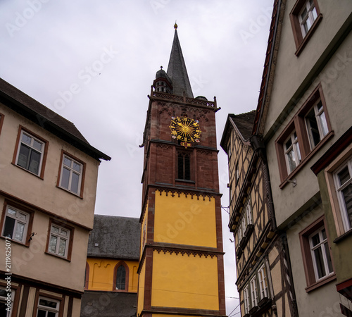 Historic church tower with clock and surrounding buildings.