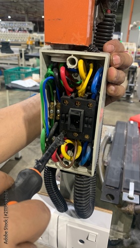 Fotografie Technician inspecting and tightening connections inside an industrial electrical