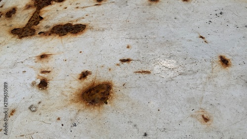 Rust spots and corrosion marks on a painted metal surface indicate material degradation from prolonged environmental exposure