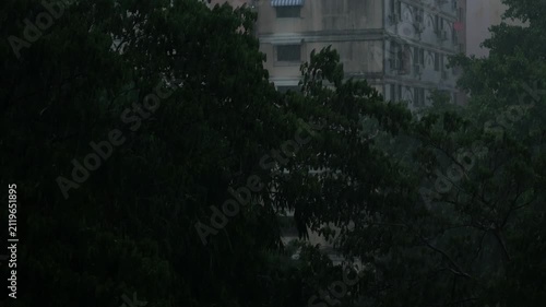 Stormy Monsoon Rain Over Old Residential Apartment Buildings with Satellite Dishes and Green Trees, Dark Gloomy Urban Cityscape