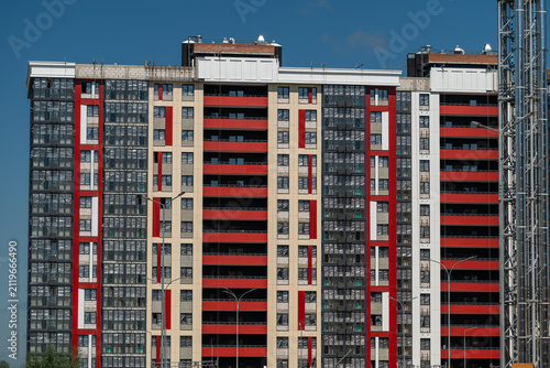 City buildings stand tall under a clear blue sky with red and beige designs showcasing modern urban architecture in a lively neighborhood