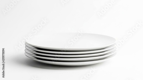Stack of six plain white ceramic plates on white surface