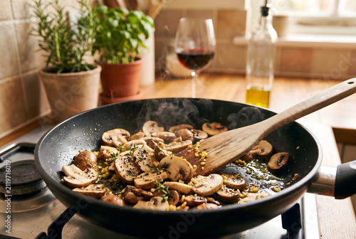 Sautéing Fresh Mushrooms in a Frying Pan on a Kitchen Stove