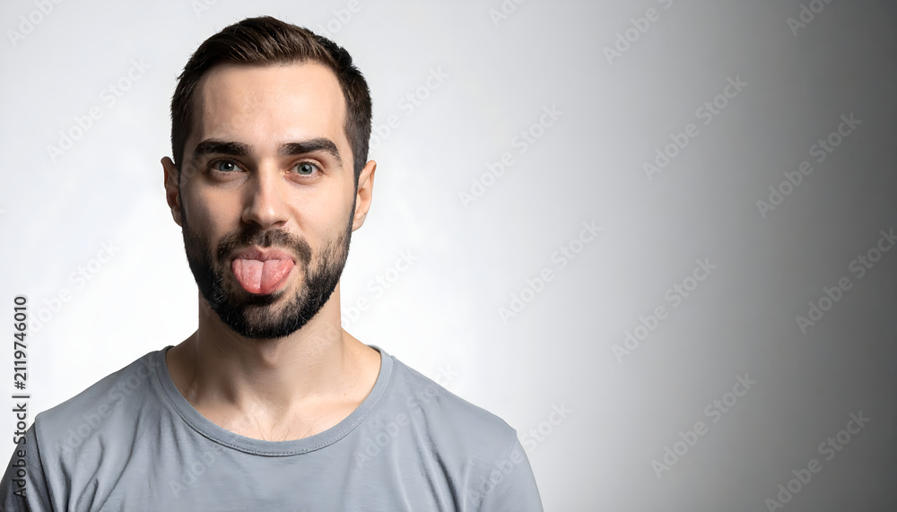Fototapeta premium Young man stands sticking tongue out wearing charcoal shirt for tech gadget advertising atmosphere generative AI