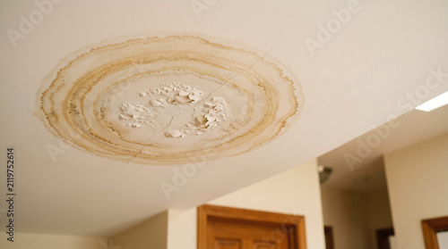 Foto Stained water damage circular mark on white ceiling plaster signs of leaking roo