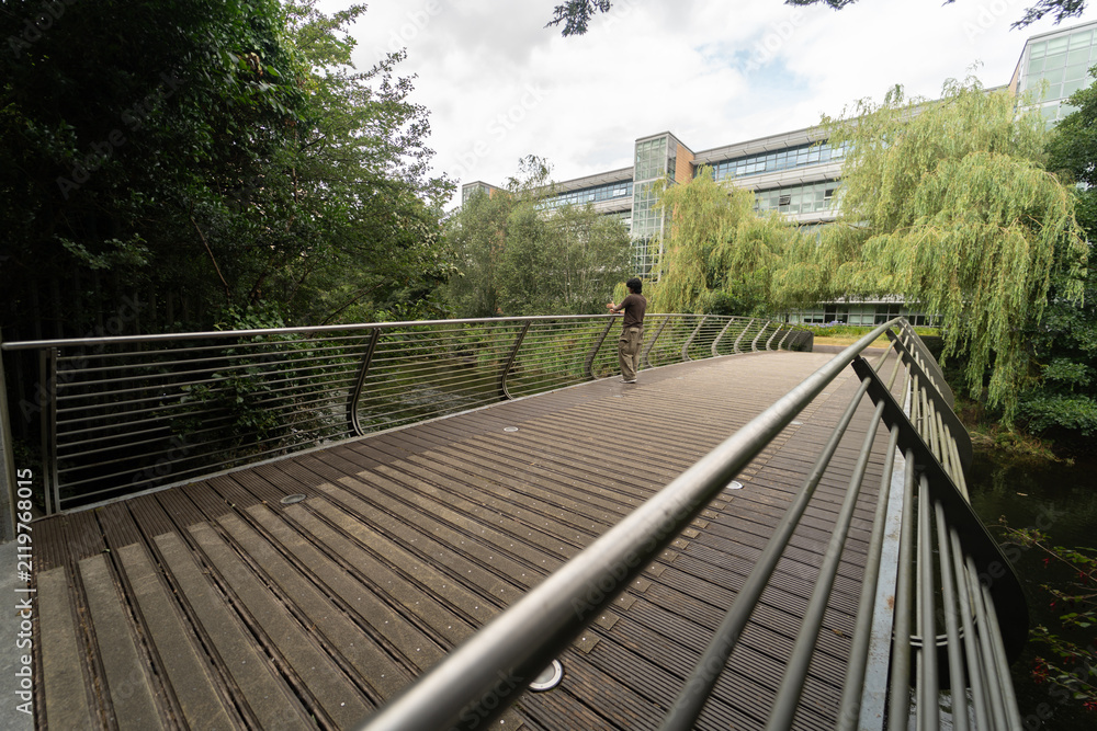 Obraz premium Person walking on modern wooden bridge by office building