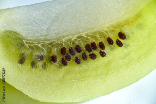 Close-up macro shot of fresh green kiwi fruit slice showing dark seeds and texture