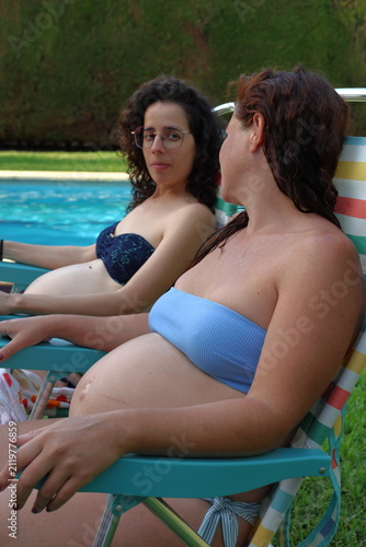 Cuadro en lienzo Expectant sisters enjoy a quiet poolside moment during a summer holiday