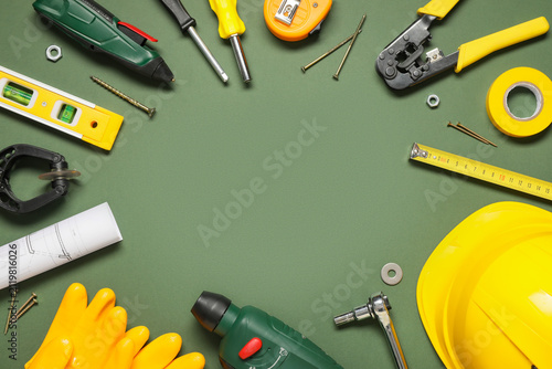 Frame made from different construction tools and hardhat on green background
