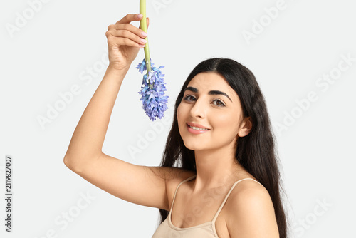 Pretty young woman with hyacinth flower on white background
