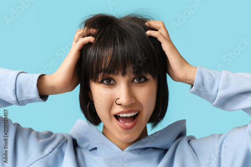 Stylish young woman with nose piercing on blue background