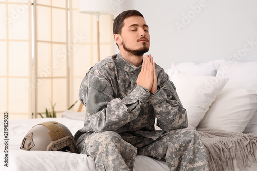 Young male soldier praying ...