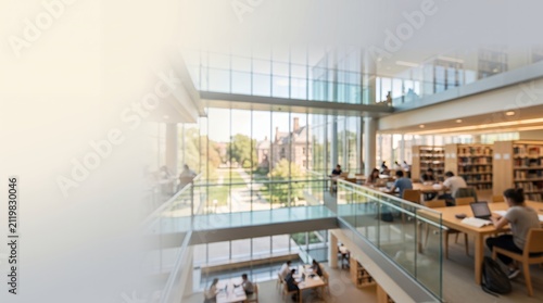 Blurred modern university library interior background with students studying at wooden tables near large windows, bright spacious campus learning hall mockup copy space background scene
