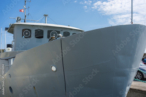 Close up of a grey ship bow docked in a harbor under a clear blue sky
