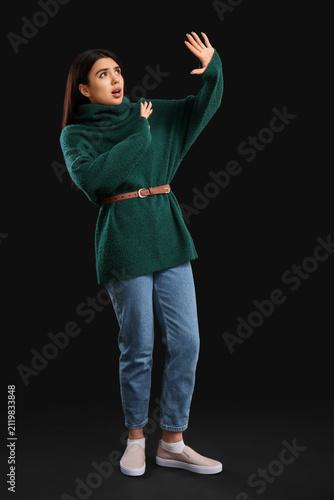 Scared young woman on black...