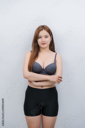 Photography Portrait of Woman: A young woman with long, brown hair stands confidently, wearing a gray bra and black shorts, her arms crossed, with a slight smile