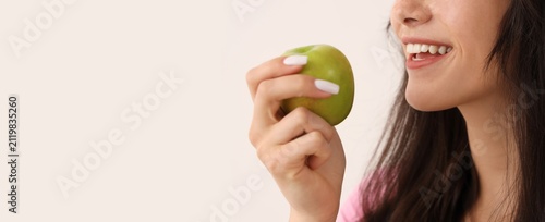 фотографія Young woman with healthy white teeth smiling while holding a fresh green apple,