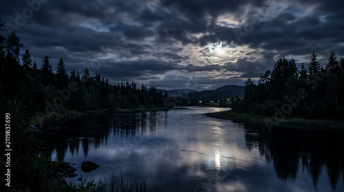 Moonlit forest lake reflecting stormy sky at dusk Generative AI