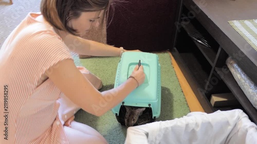 Young Woman Tending to Her Domestic Rabbit in a Blue Plastic Pet Carrier at Home