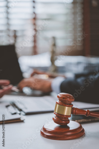 Foto Gavel on table with legal professionals discussing documents