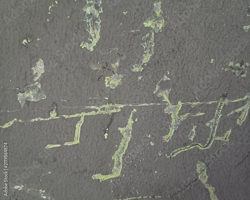 Close-up of dark grey textured wall with scratches and peeling paint layer.