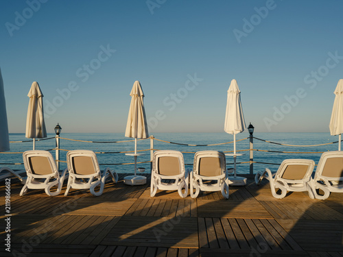 Fotografía Sun loungers and umbrellas on a wooden beach pier